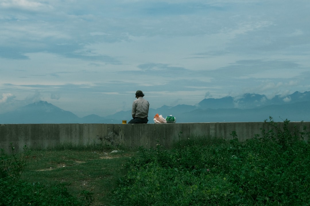 a person and a child sitting on a stone wall overlooking a field