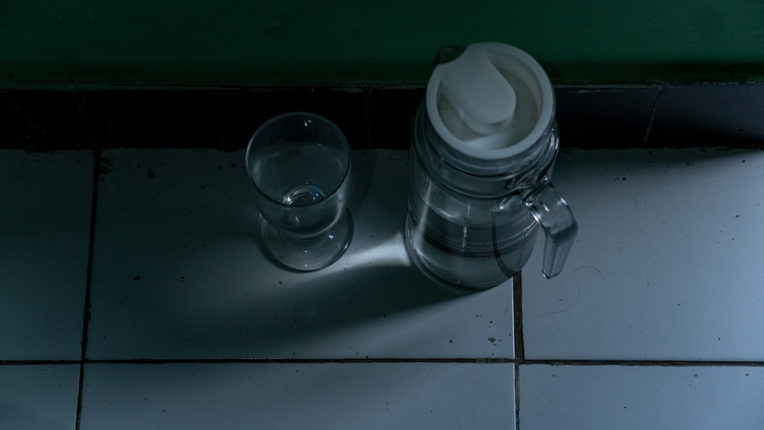 A glass of water sitting on top of a tiled floor