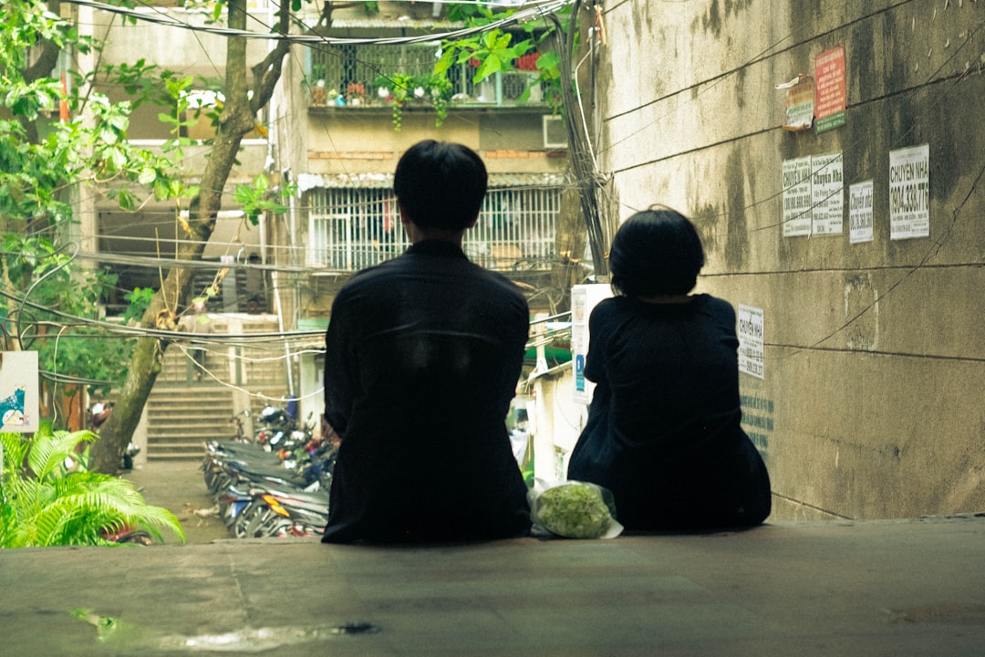 a couple of people sitting on top of a cement floor